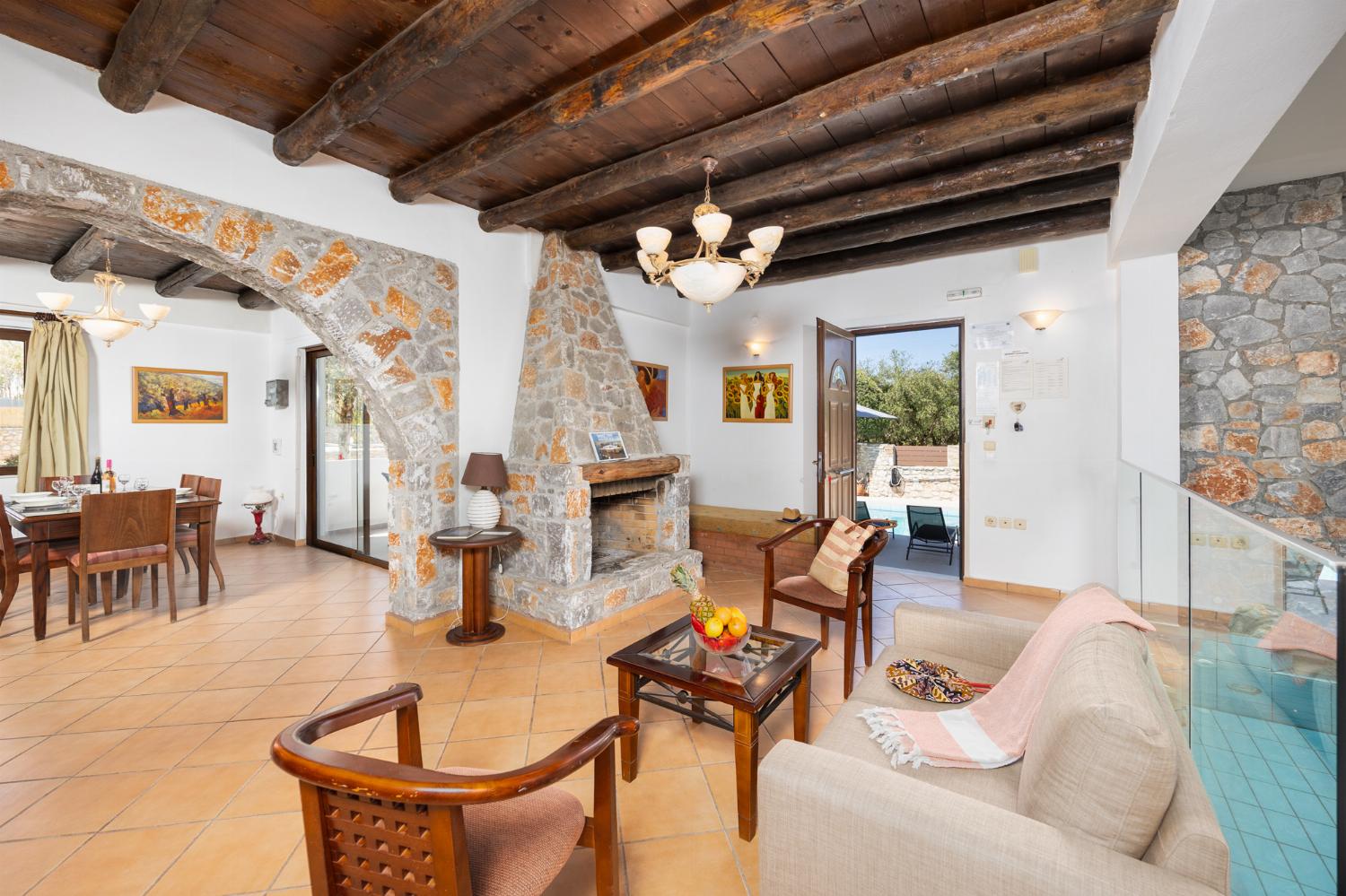 Open-plan living room with sofa, dining area, kitchen, indoor pool, ornamental fireplace, A/C, WiFi internet, and satellite TV