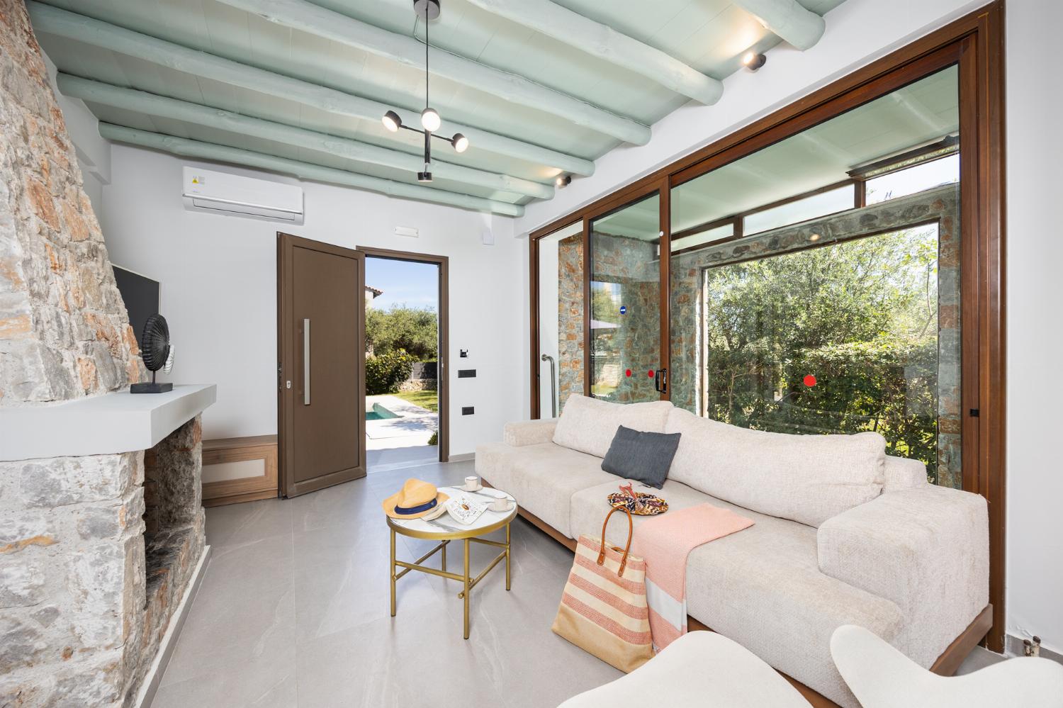 Open-plan living room with sofa, dining area, kitchen, indoor pool, ornamental fireplace, A/C, WiFi internet, and satellite TV
