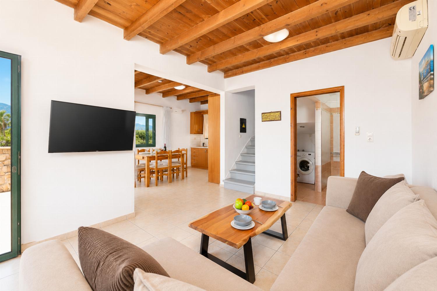 Open-plan living room with sofa, dining area, kitchen, A/C, WiFi internet, and satellite TV