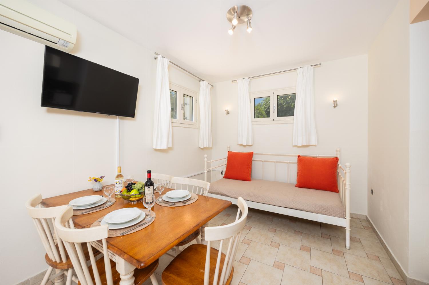 Open-plan living room with sofa, dining area, kitchen, ornamental fireplace, A/C, WiFi internet, and satellite TV