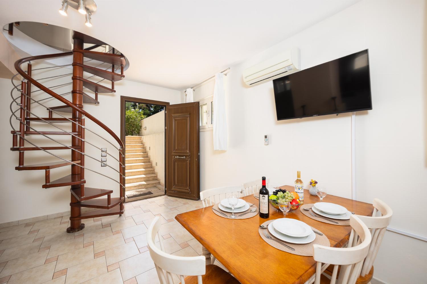 Open-plan living room with sofa, dining area, kitchen, ornamental fireplace, A/C, WiFi internet, and satellite TV