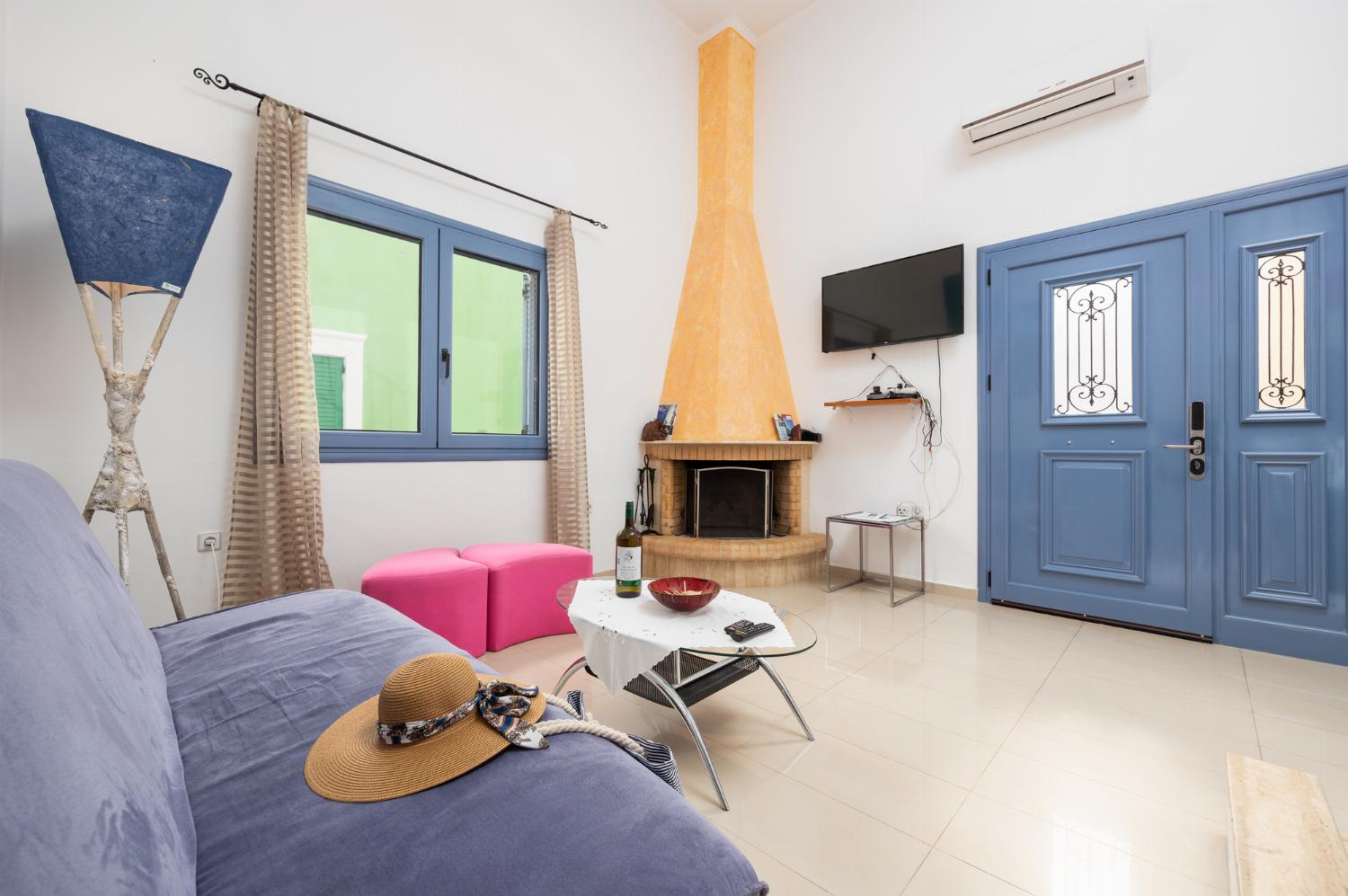 Open-plan living room with sofa, dining area, kitchen, ornamental fireplace, A/C, WiFi internet, and satellite TV