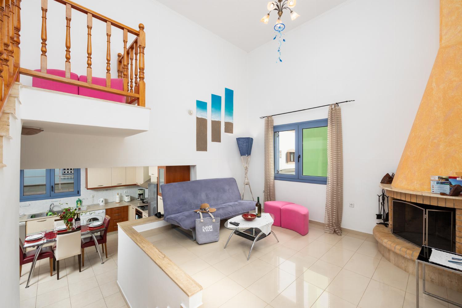 Open-plan living room with sofa, dining area, kitchen, ornamental fireplace, A/C, WiFi internet, and satellite TV