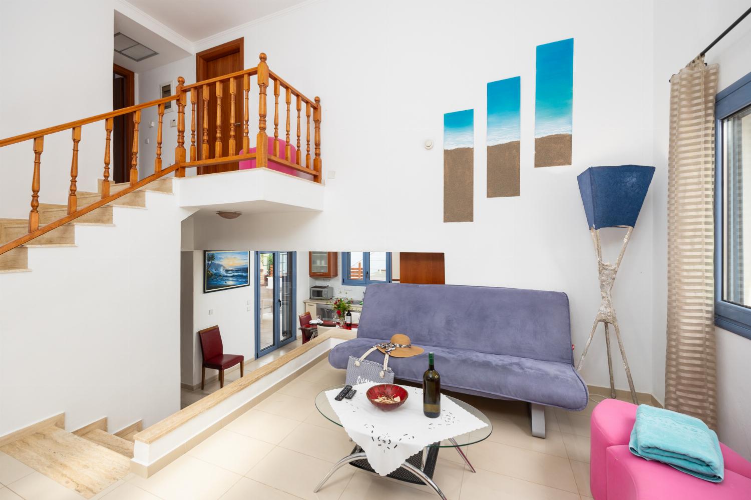 Open-plan living room with sofa, dining area, kitchen, ornamental fireplace, A/C, WiFi internet, and satellite TV