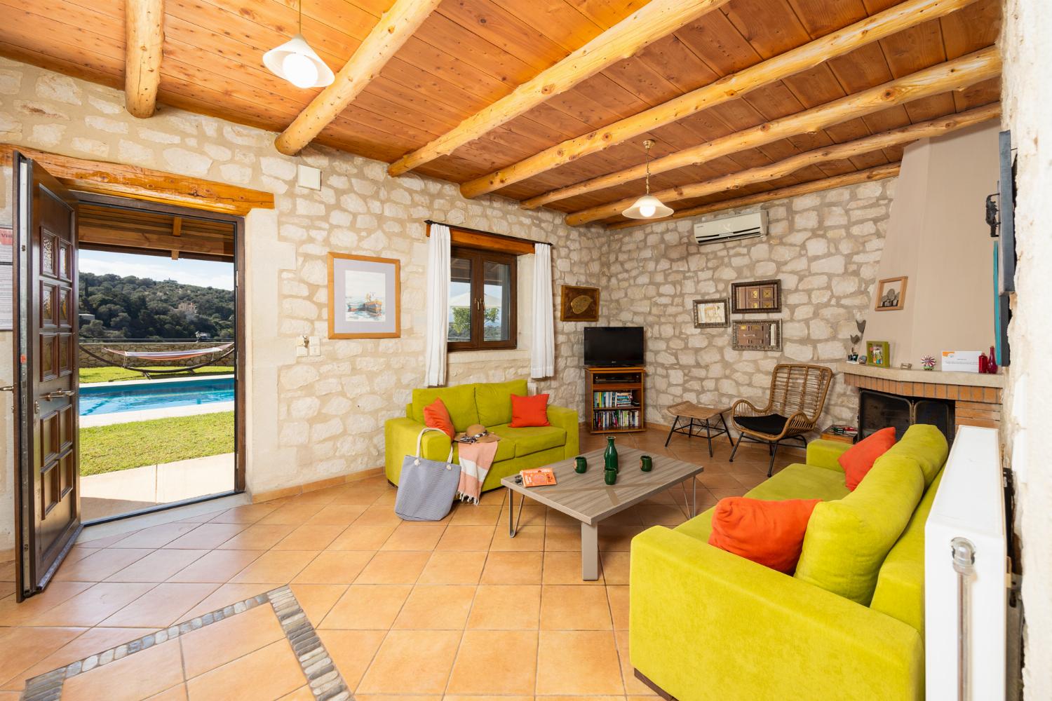 Open-plan living room with sofas, dining area, kitchen, ornamental fireplace, A/C, WiFi internet, and satellite TV