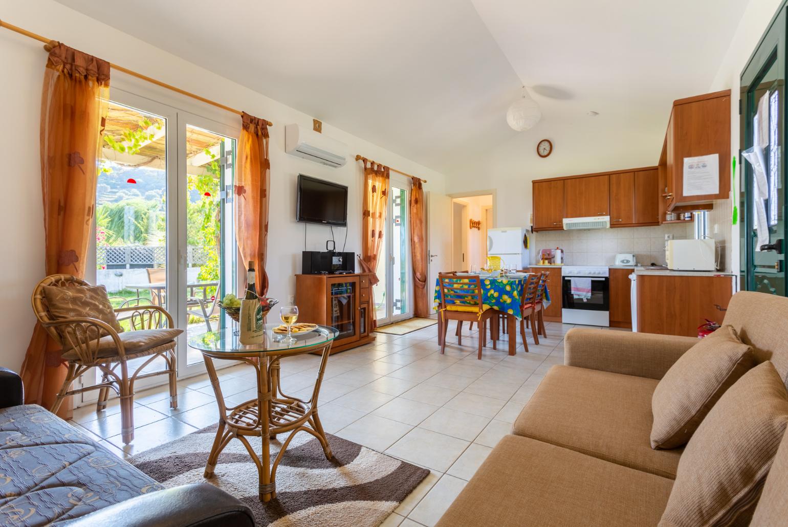 Open-plan living room with sofas, dining area, kitchen, ornamental fireplace, A/C, WiFi internet, satellite TV, and terrace access