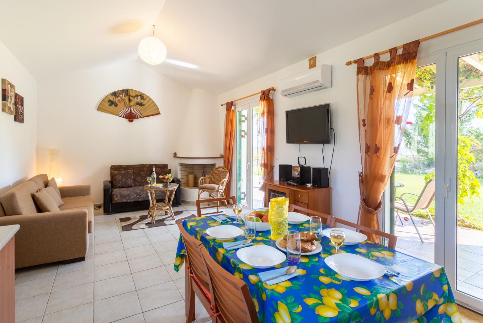 Open-plan living room with sofas, dining area, kitchen, ornamental fireplace, A/C, WiFi internet, satellite TV, and terrace access