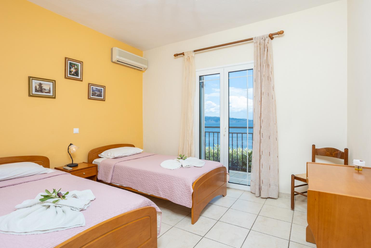 Twin bedroom with en suite bathroom, A/C, terrace access, and sea views