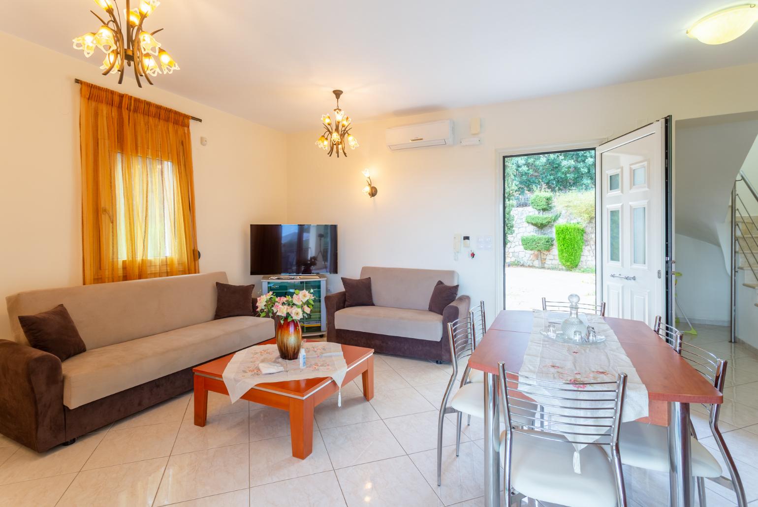 Open-plan living room with sofas, dining area, kitchen, A/C, WiFi internet, satellite TV, DVD player, and terrace access