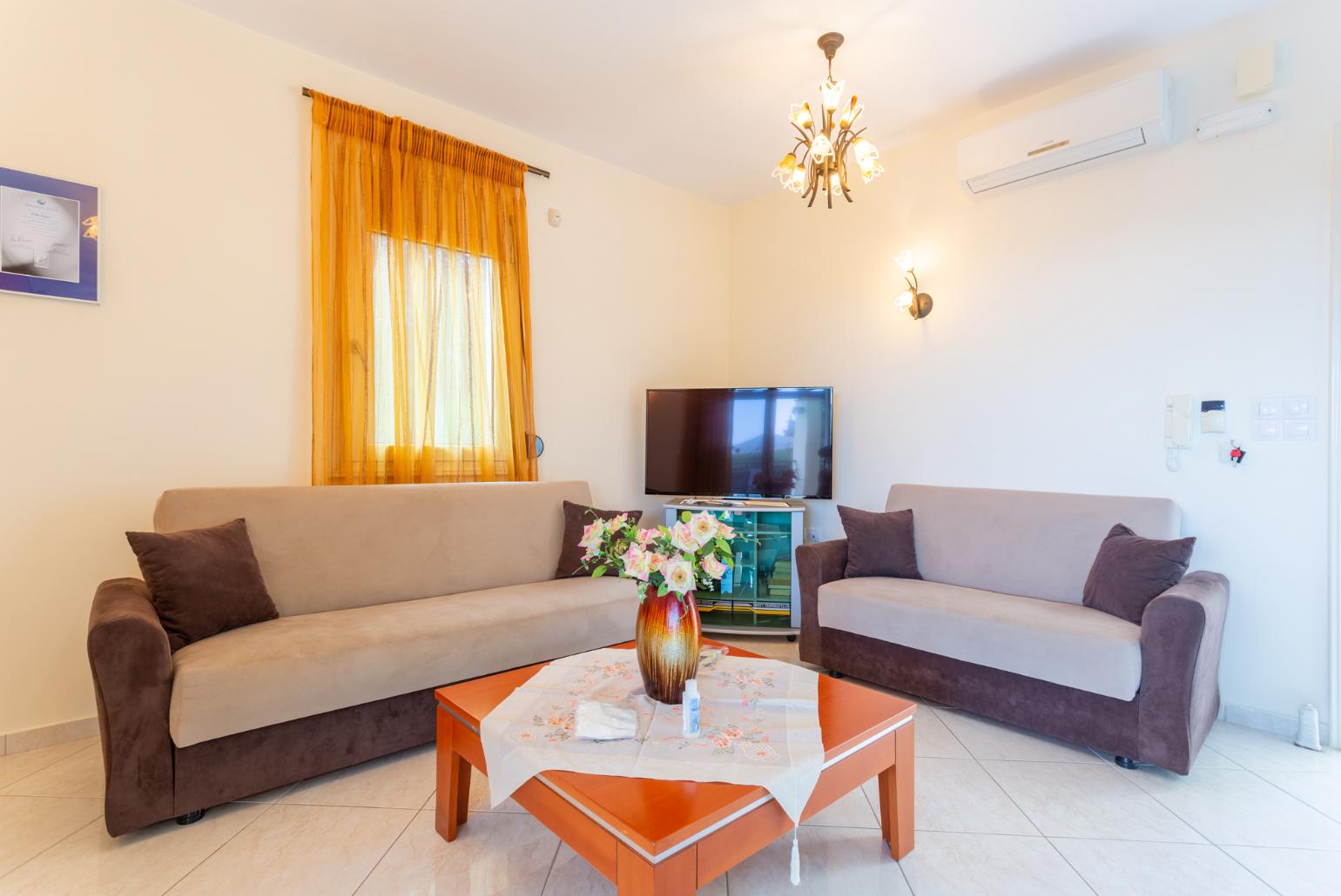 Open-plan living room with sofas, dining area, kitchen, A/C, WiFi internet, satellite TV, DVD player, and terrace access