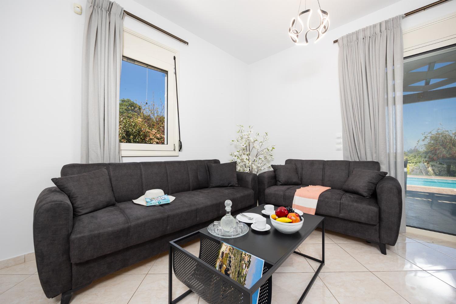 Open-plan living room with sofas, dining area, kitchen, A/C, WiFi internet, and satellite TV
