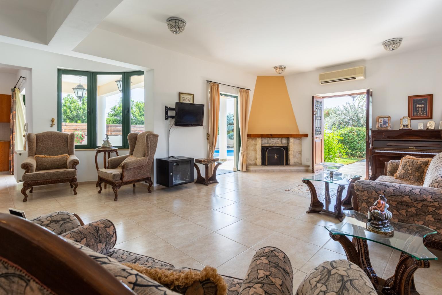 Open-plan living room with sofas, dining area, kitchen, ornamental fireplace, A/C, WiFi internet, satellite TV, and terrace access