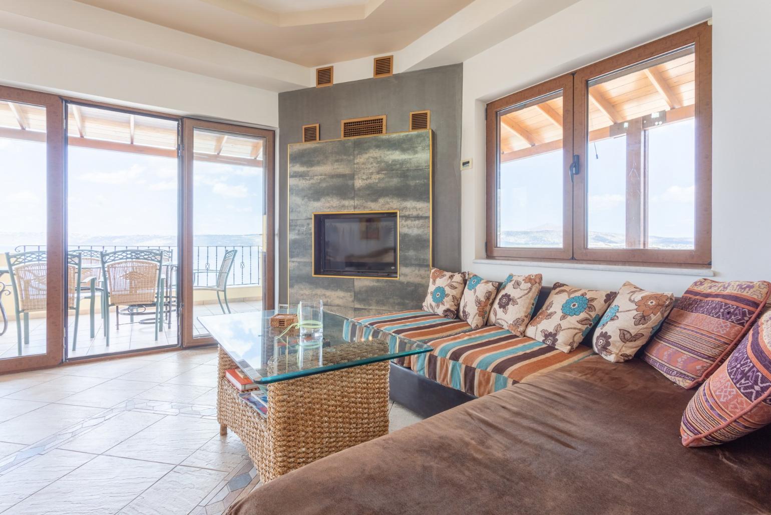Open-plan living room with sofas, dining area, kitchen, WiFi internet, satellite TV, DVD player, and balcony access with panoramic sea views