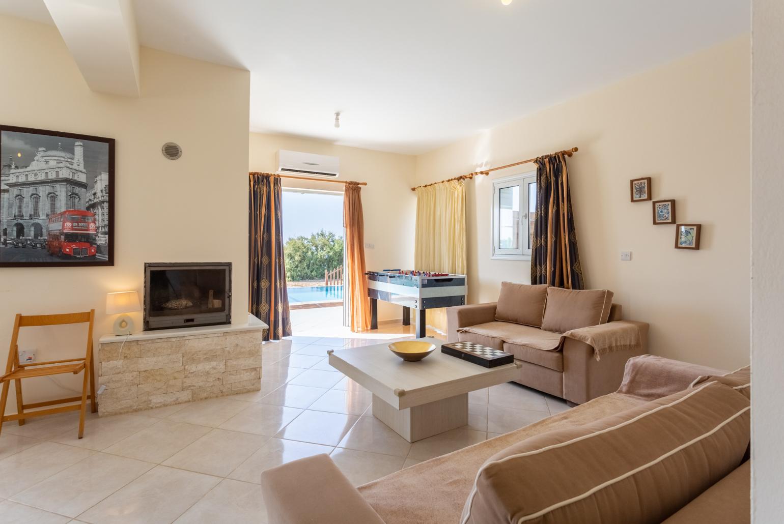 Open-plan living room with sofas, dining area, kitchen, ornamental fireplace, A/C, WiFi internet, satellite TV, pool table, foosball table, and terrace access with sea views