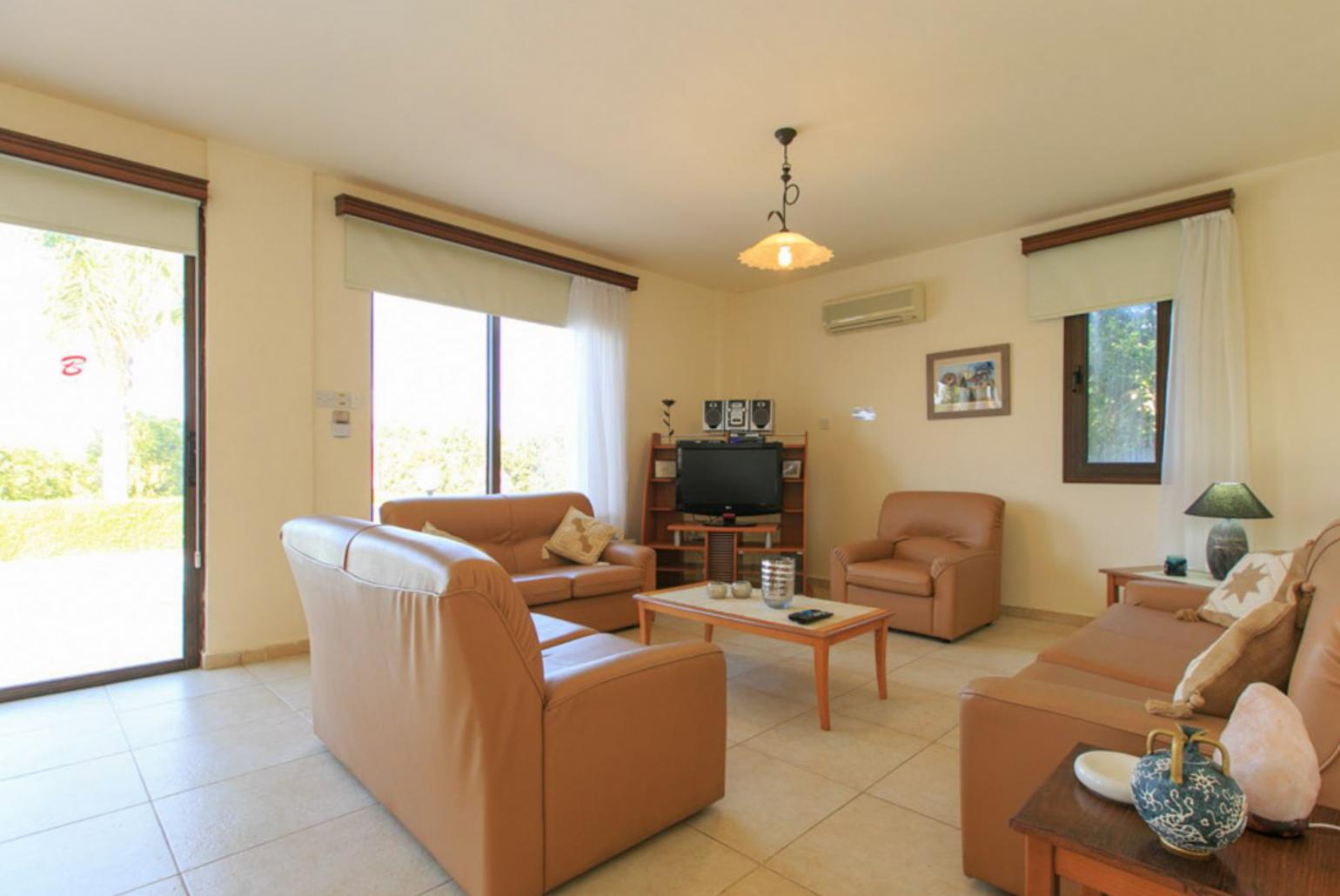 Open-plan living room with sofas, dining area, kitchen, A/C, WiFi internet, satellite TV, DVD player, and terrace access