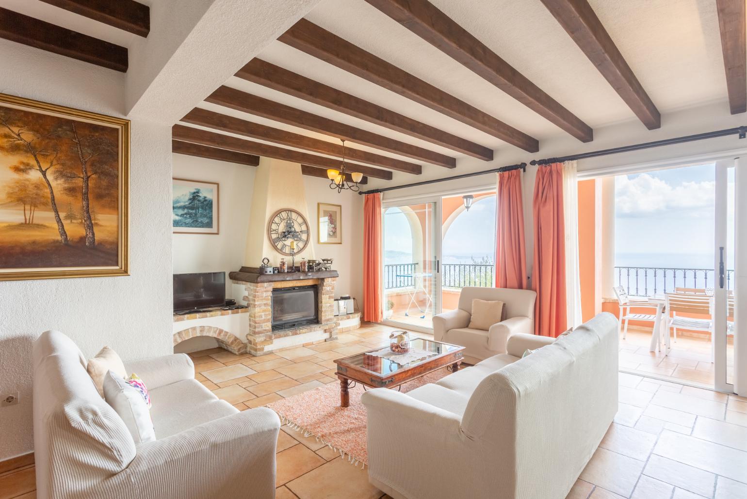 Open-plan living room with sofas, dining areas, kitchen, ornamental fireplace, WiFi internet, satellite TV, and terrace access with panoramic sea views