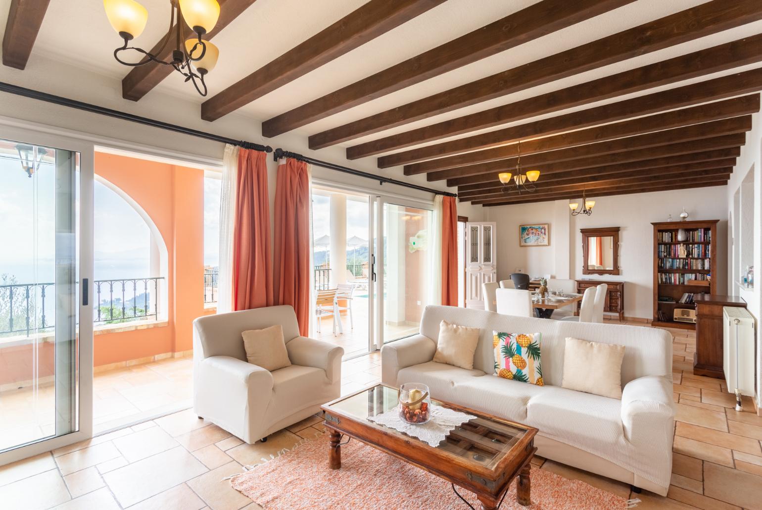 Open-plan living room with sofas, dining areas, kitchen, ornamental fireplace, WiFi internet, satellite TV, and terrace access with panoramic sea views