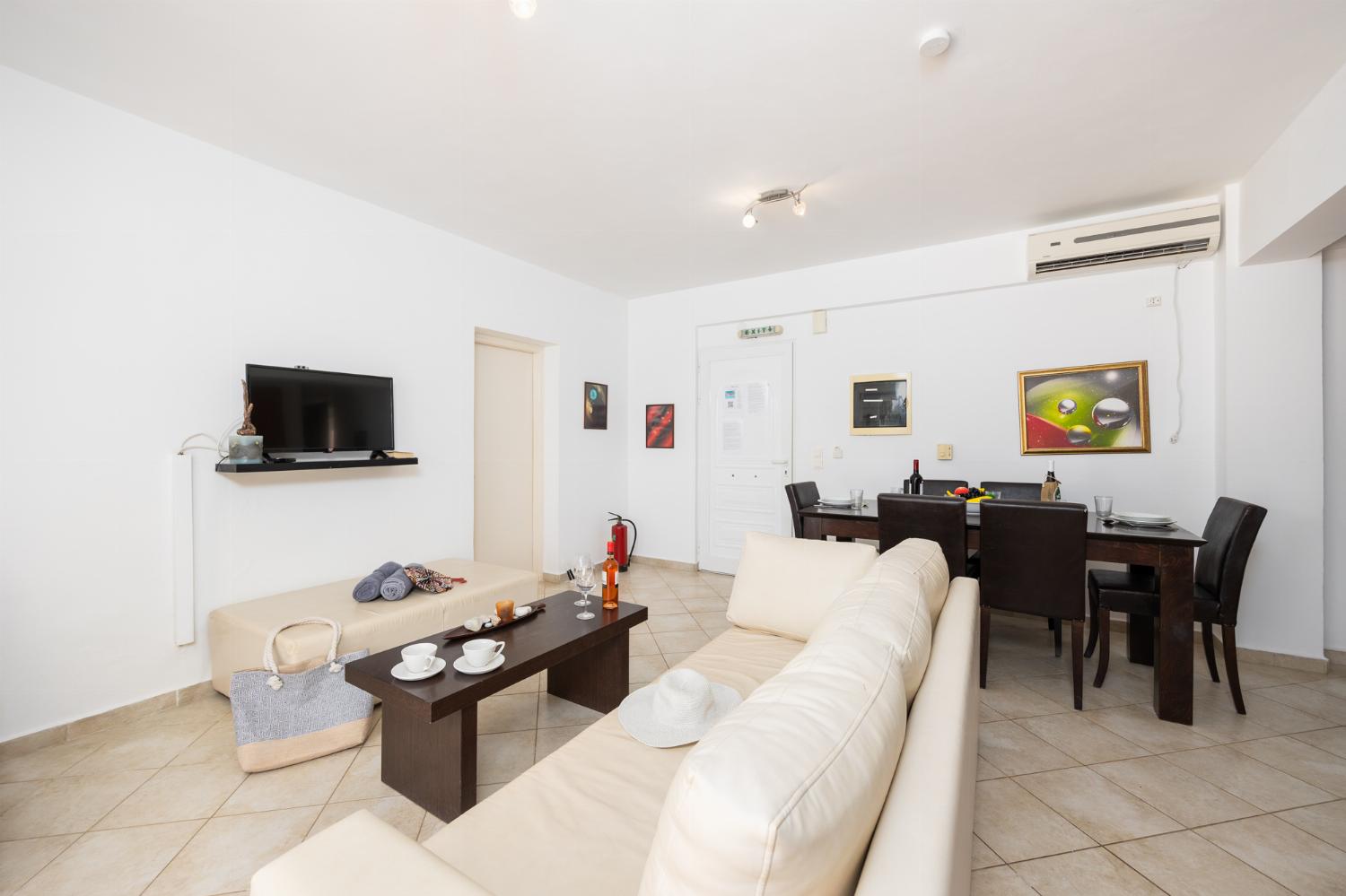 Open-plan living room with sofa, dining area, kitchen, A/C, WiFi internet, and satellite TV