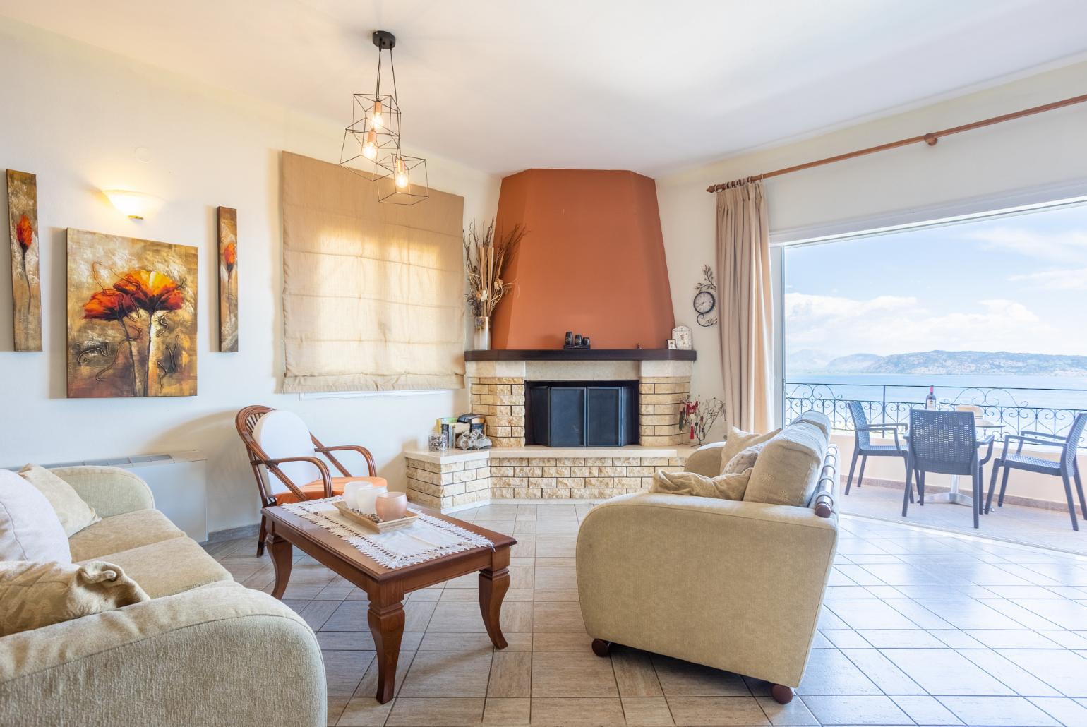Open-plan living room with sofas, dining area, kitchen, ornamental fireplace, WiFi internet, satellite TV, and balcony access with panoramic sea views