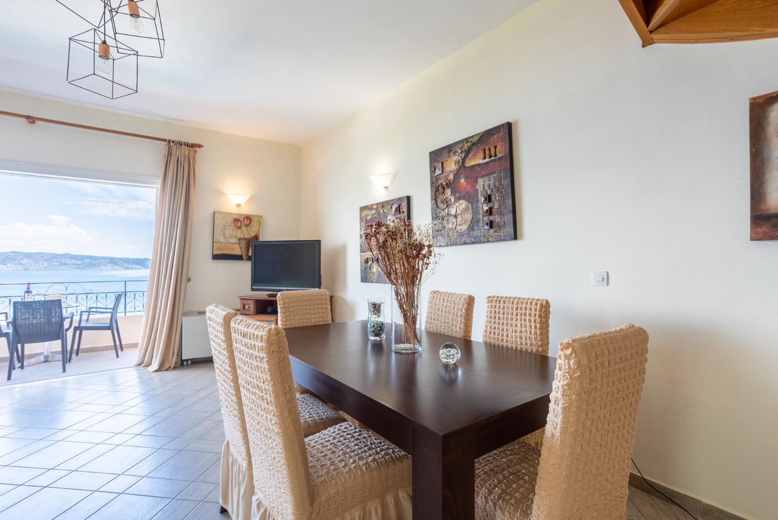Open-plan living room with sofas, dining area, kitchen, ornamental fireplace, WiFi internet, satellite TV, and balcony access with panoramic sea views