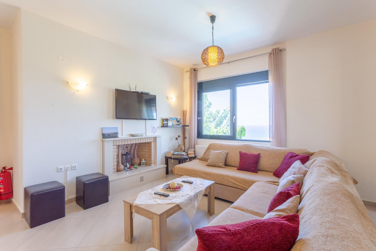 Open-plan living room with sofas, dining area, kitchen, ornamental fireplace, WiFi internet, satellite TV, and terrace access