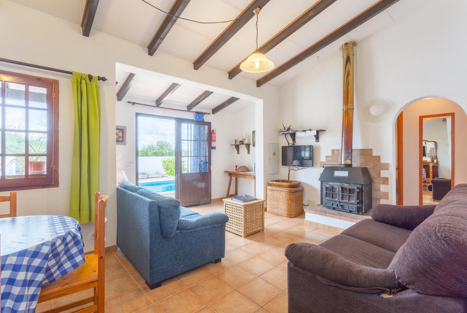 Living room with sofas, dining area, ornamental fireplace, A/C, WiFi internet, satellite TV, DVD player, and pool terrace access