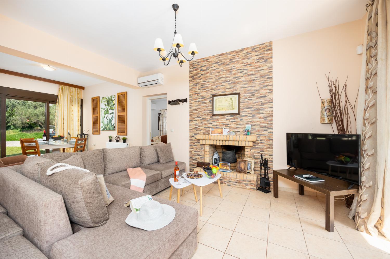 Open-plan living room with sofa, dining areas, kitchen, ornamental fireplace, A/C, WiFi internet, A/C, and satellite TV