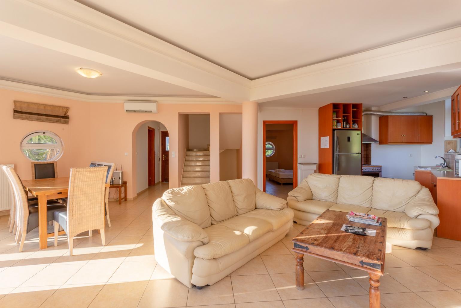 Open-plan living room on first floor with sofas, dining area, kitchen, A/C, WiFi internet, TV, DVD player, and balcony and pool terrace access