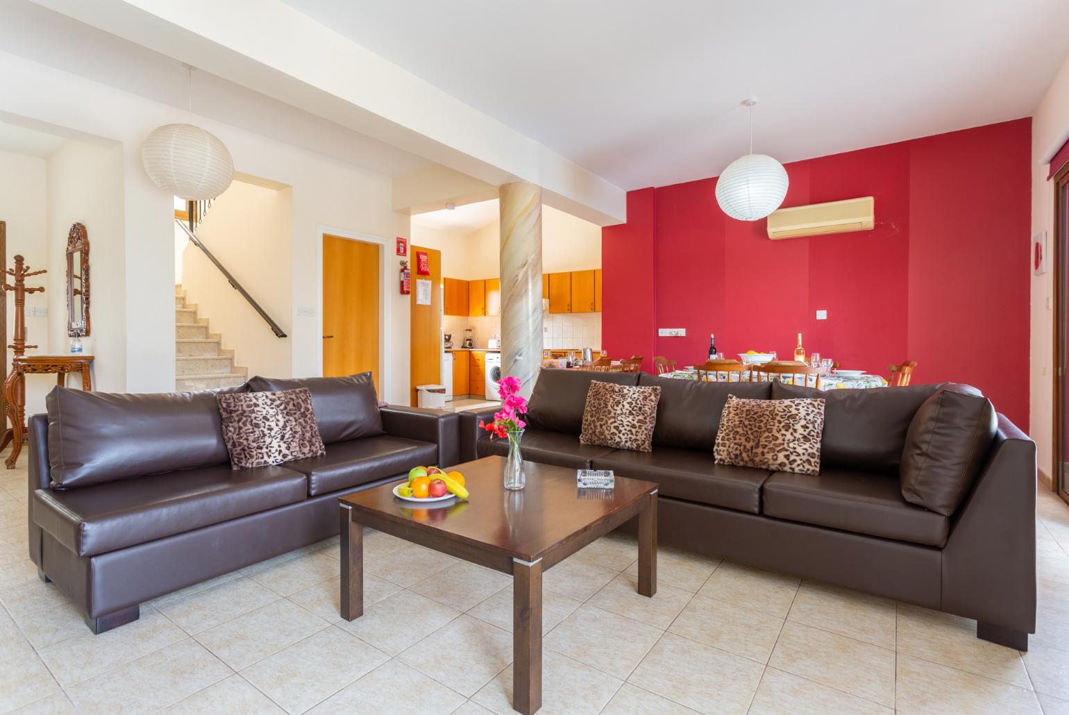 Open-plan living room with sofas, dining area, kitchen, A/C, WiFi internet, and satellite TV