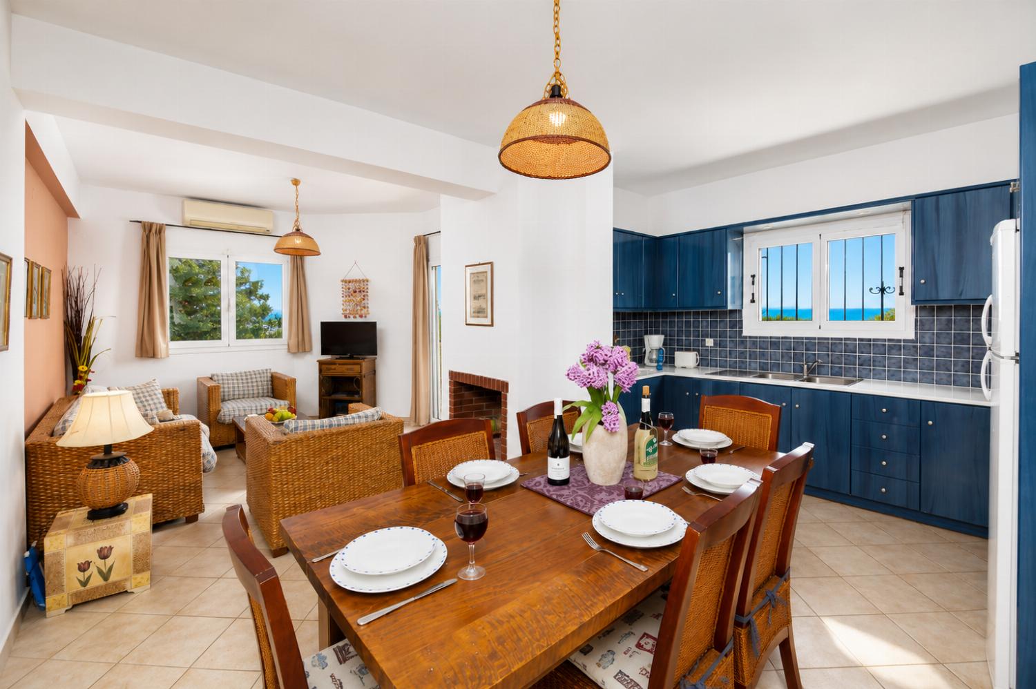 Open-plan living room with sofa, dining area, kitchen, ornamental fireplace, A/C, WiFi internet, and satellite TV