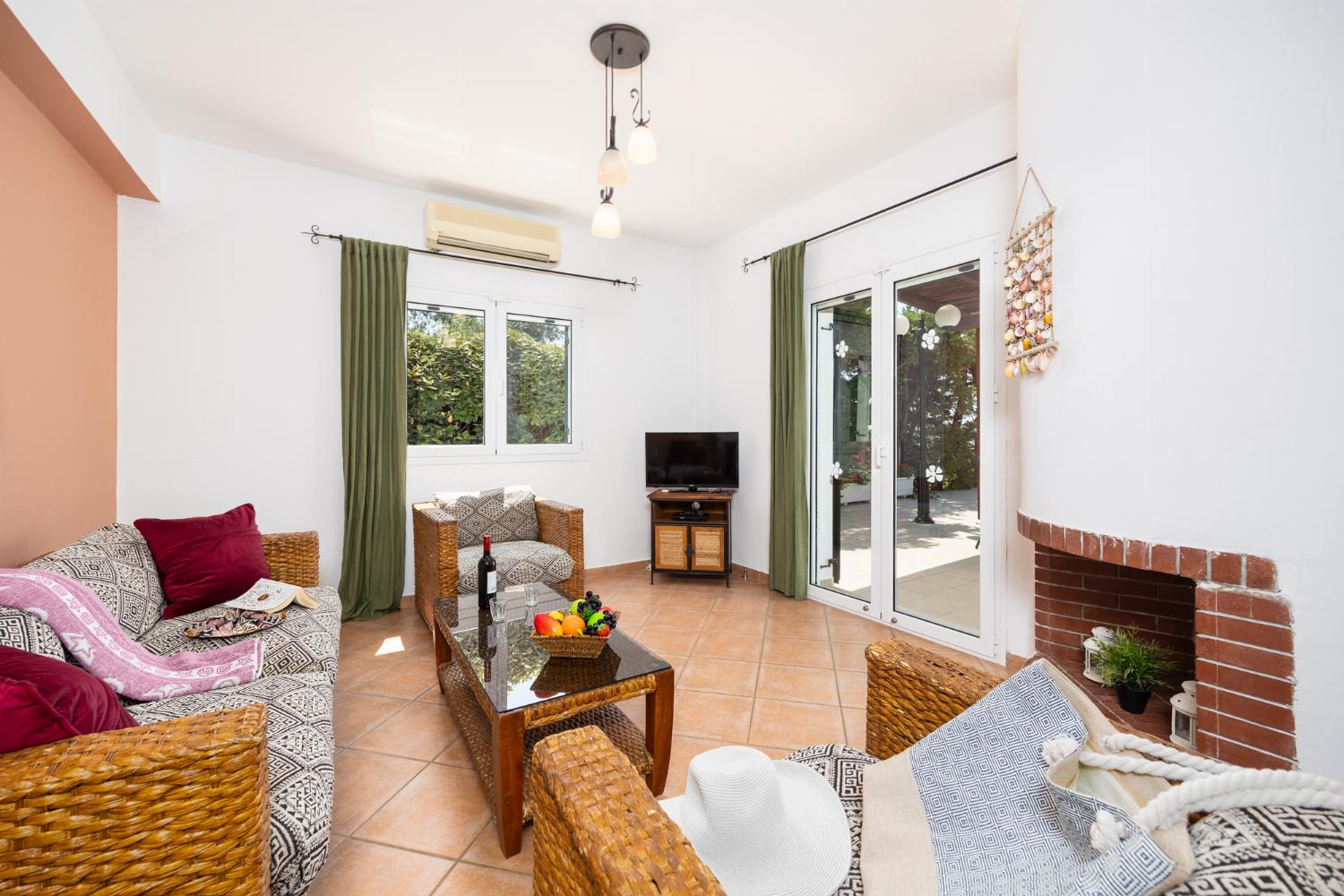 Open-plan living room with sofa, dining area, kitchen, ornamental fireplace, A/C, WiFi internet, and satellite TV
