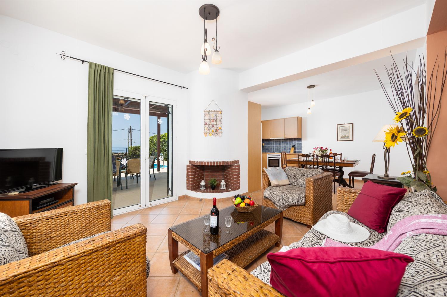 Open-plan living room with sofa, dining area, kitchen, ornamental fireplace, A/C, WiFi internet, and satellite TV