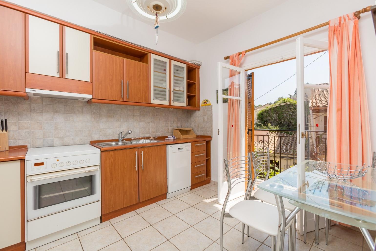 Equipped kitchen, dining area, and balcony access