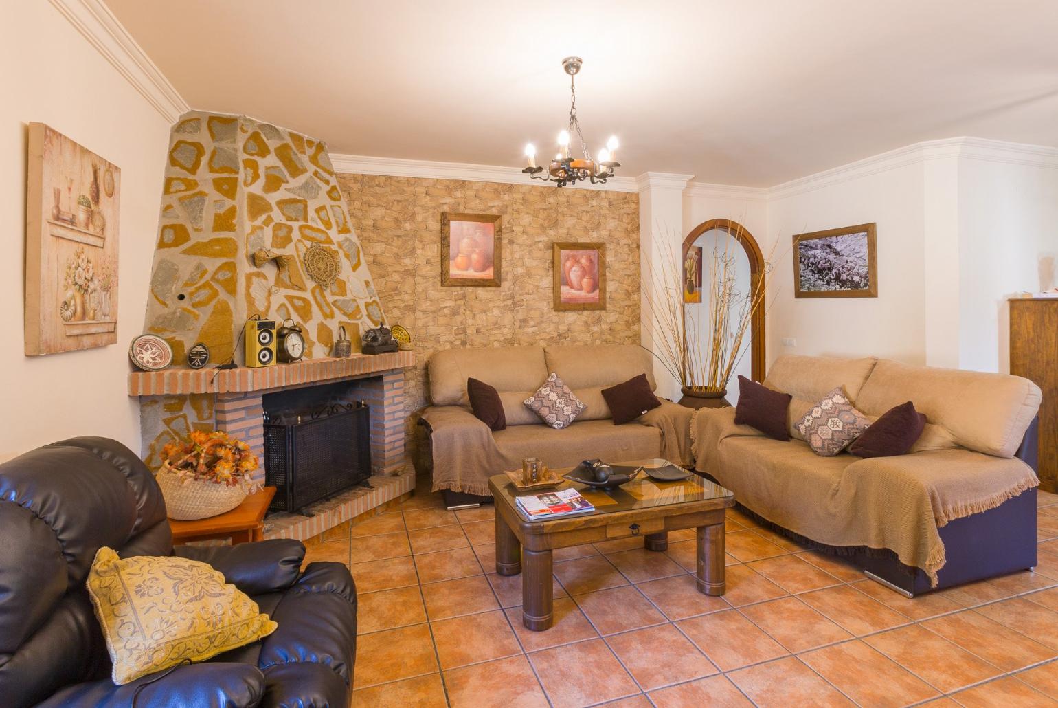 Open-plan living room with sofas, dining area, kitchen, ornamental fireplace, A/C, WiFi internet, satellite TV, DVD player, and terrace access