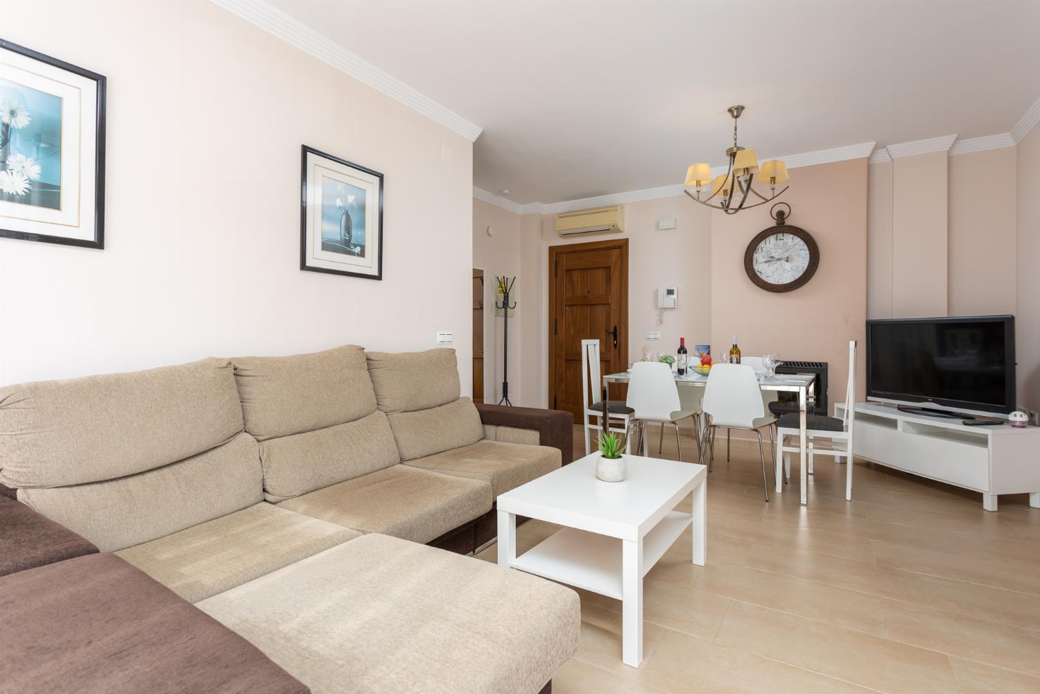 Living room with sofa, dining area, ornamental fireplace, A/C, WiFi internet, and satellite TV