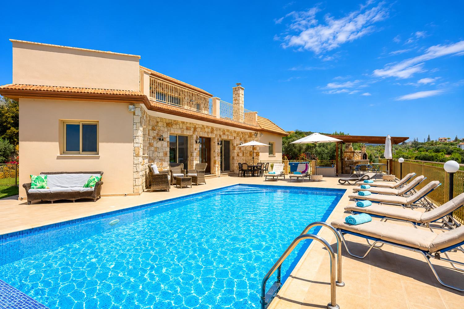 ,Sunny stone villa with a large private pool, sun loungers, and a spacious outdoor dining area.