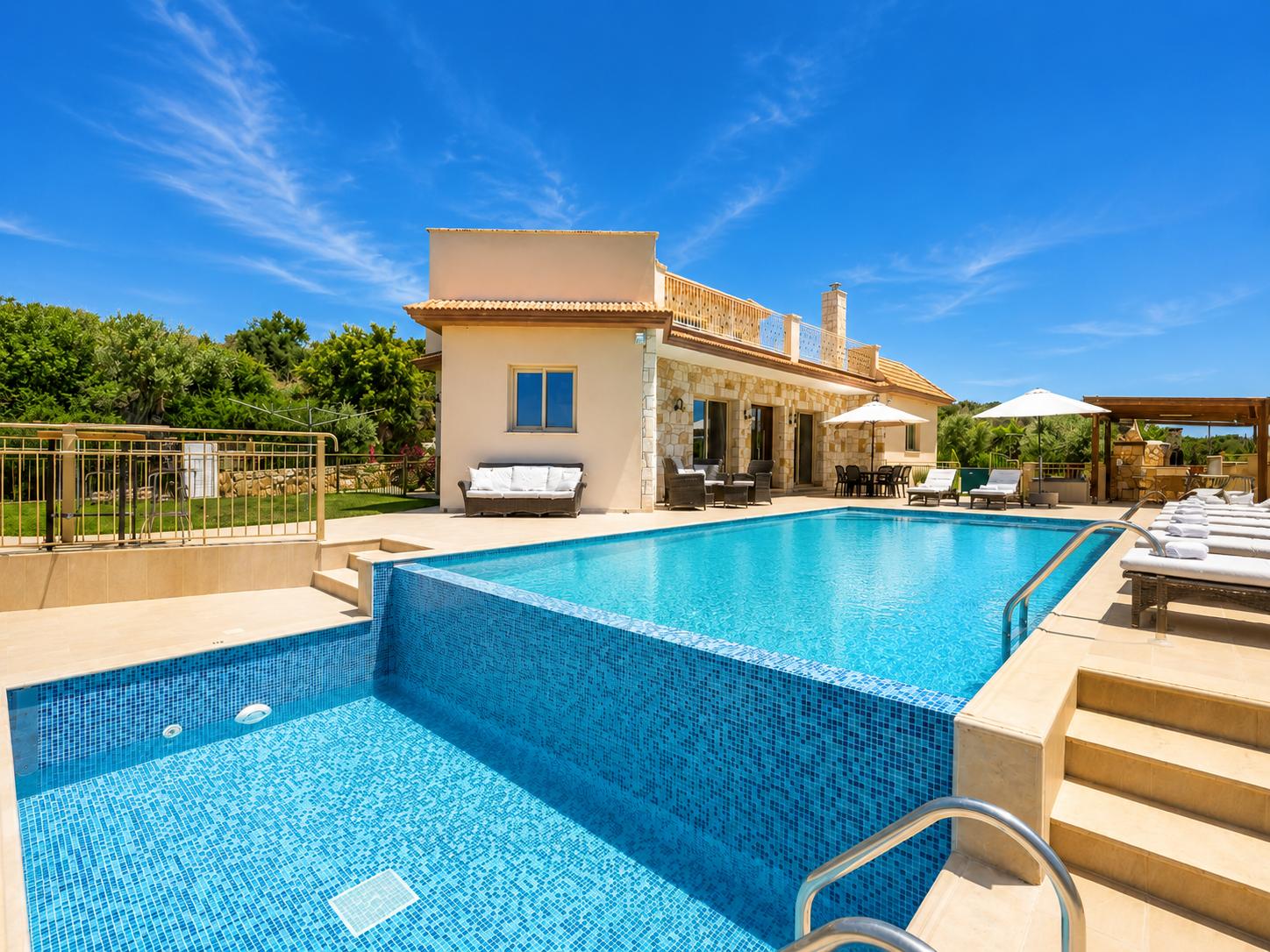 Large private pool with a beautiful stone villa, sun loungers, and a bright Mediterranean setting.