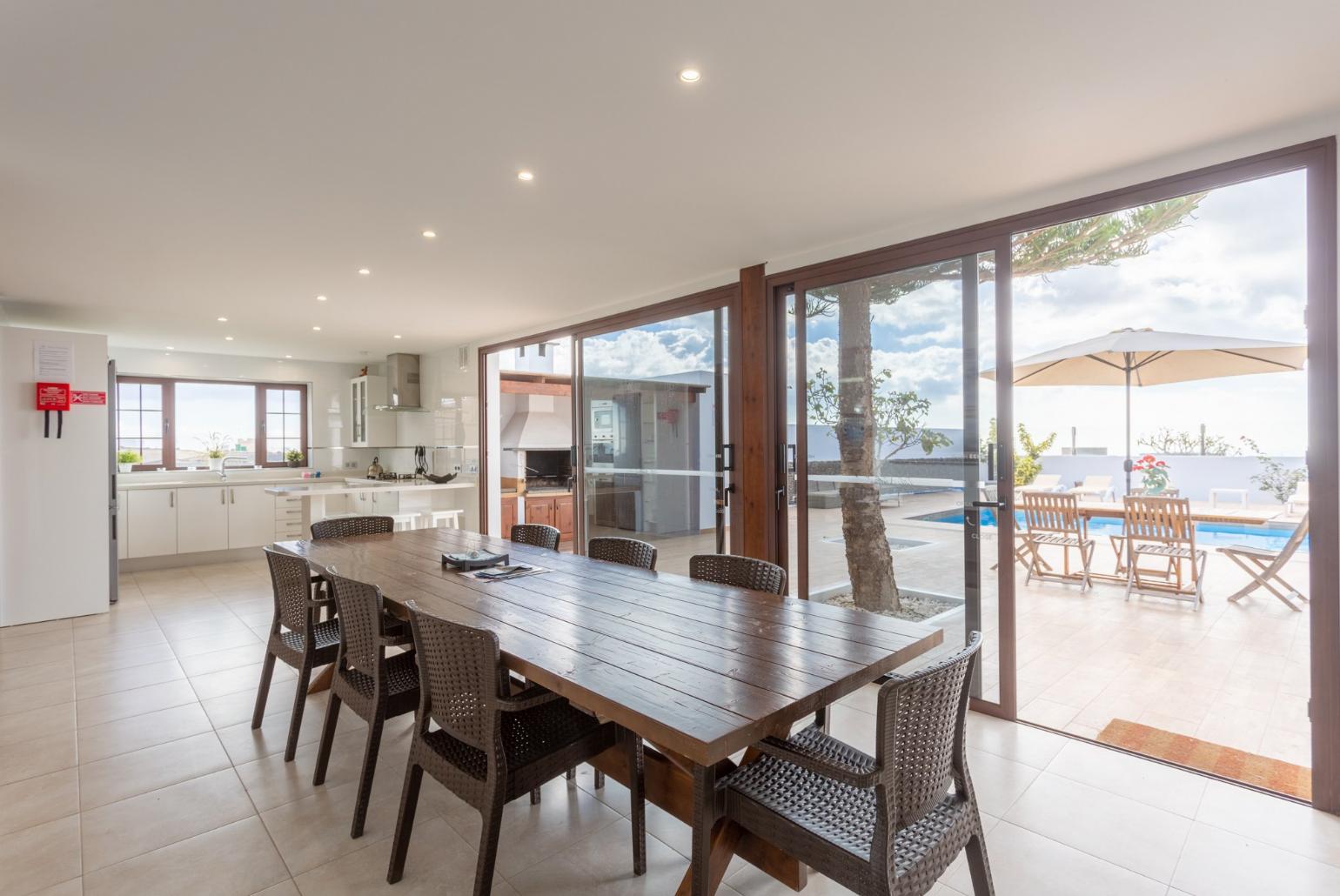 Open-plan living room with sofas, dining area, kitchen, ornamental fireplace, WiFi internet, satellite TV, DVD player, and pool terrace access