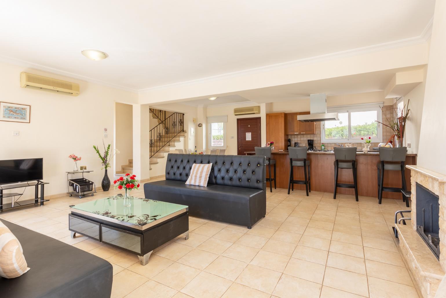 Open-plan living room with sofa, dining area, kitchen, ornamental fireplace, A/C, WiFi internet, and satellite TV