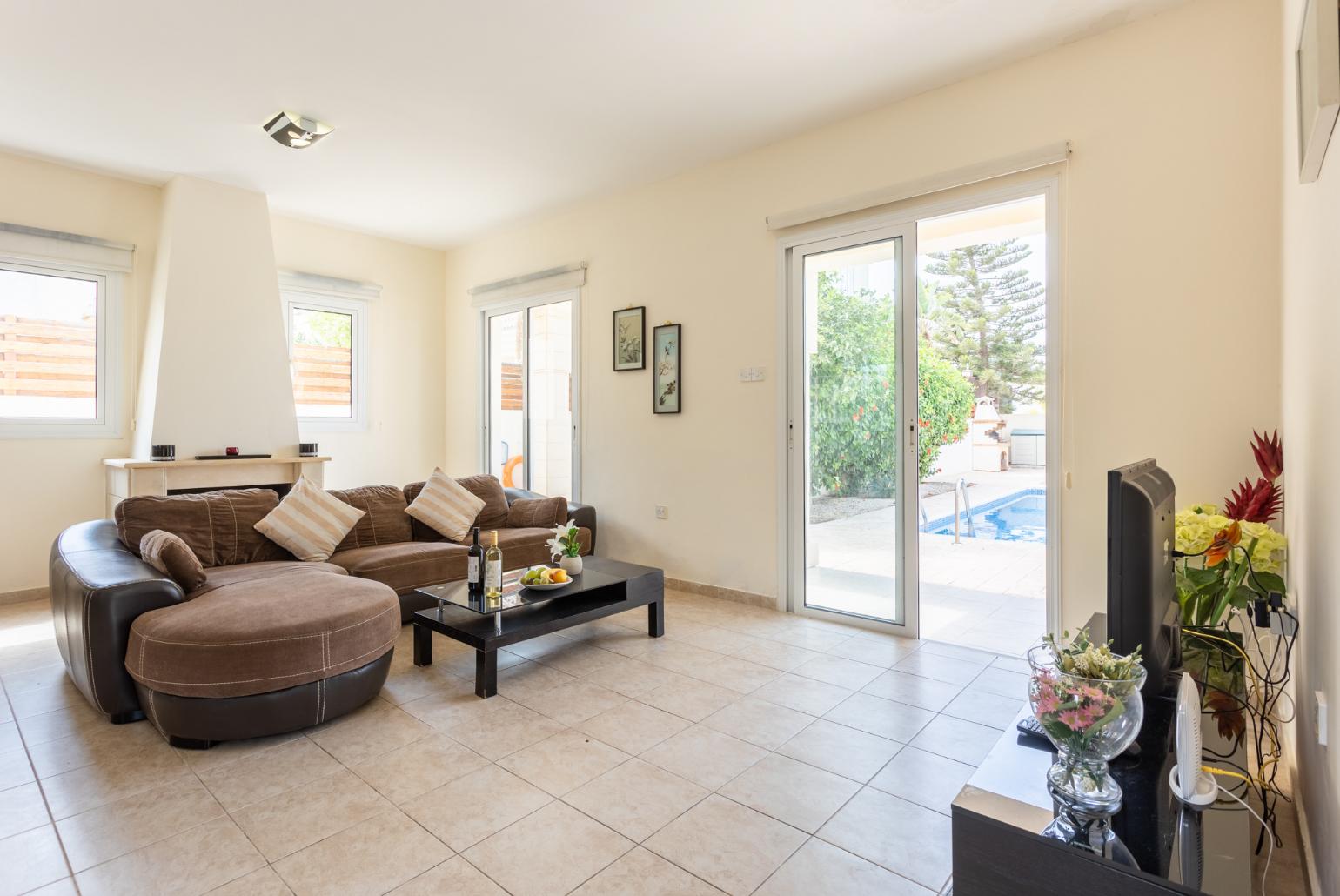 Open-plan living room with sofa, dining area, kitchen, ornamental fireplace, A/C, WiFi internet, and satellite TV