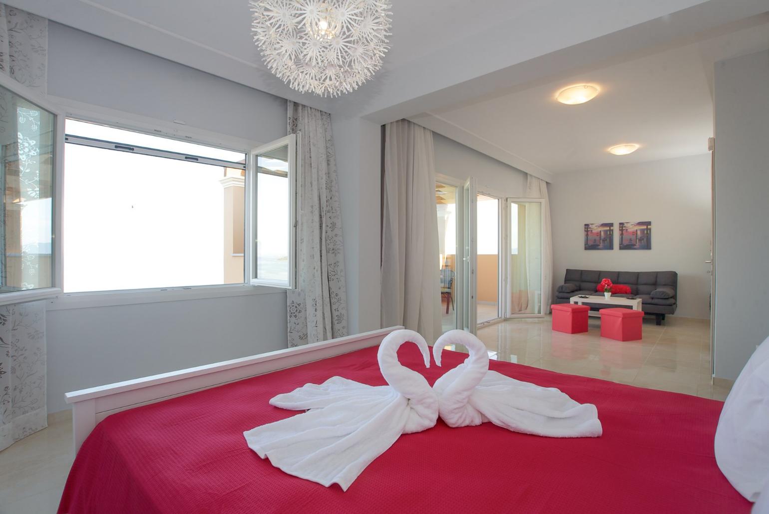 Double bedroom with en suite bathroom, A/C, living area, and balcony access with panoramic sea views