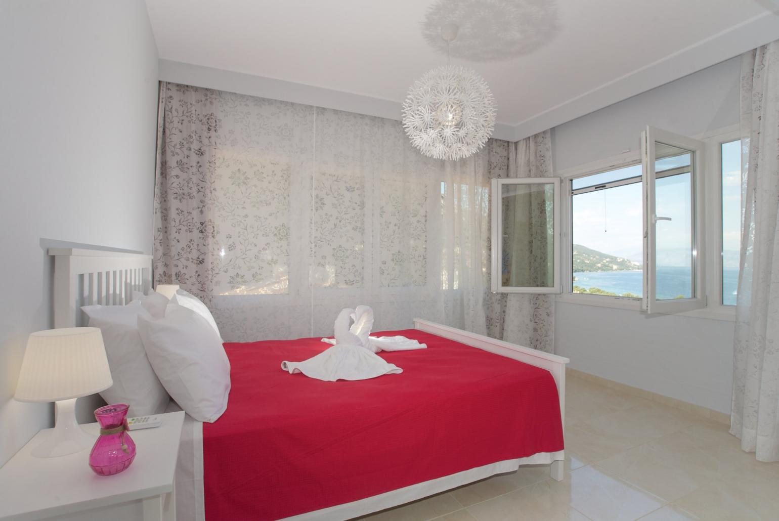 Double bedroom with en suite bathroom, A/C, living area, and balcony access with panoramic sea views