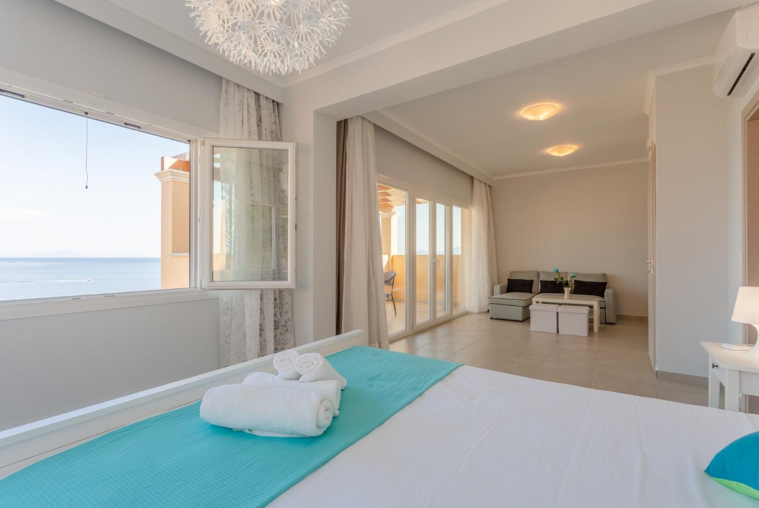 Double bedroom with en suite bathroom, A/C, living area, walk-in wardrobe, and balcony access