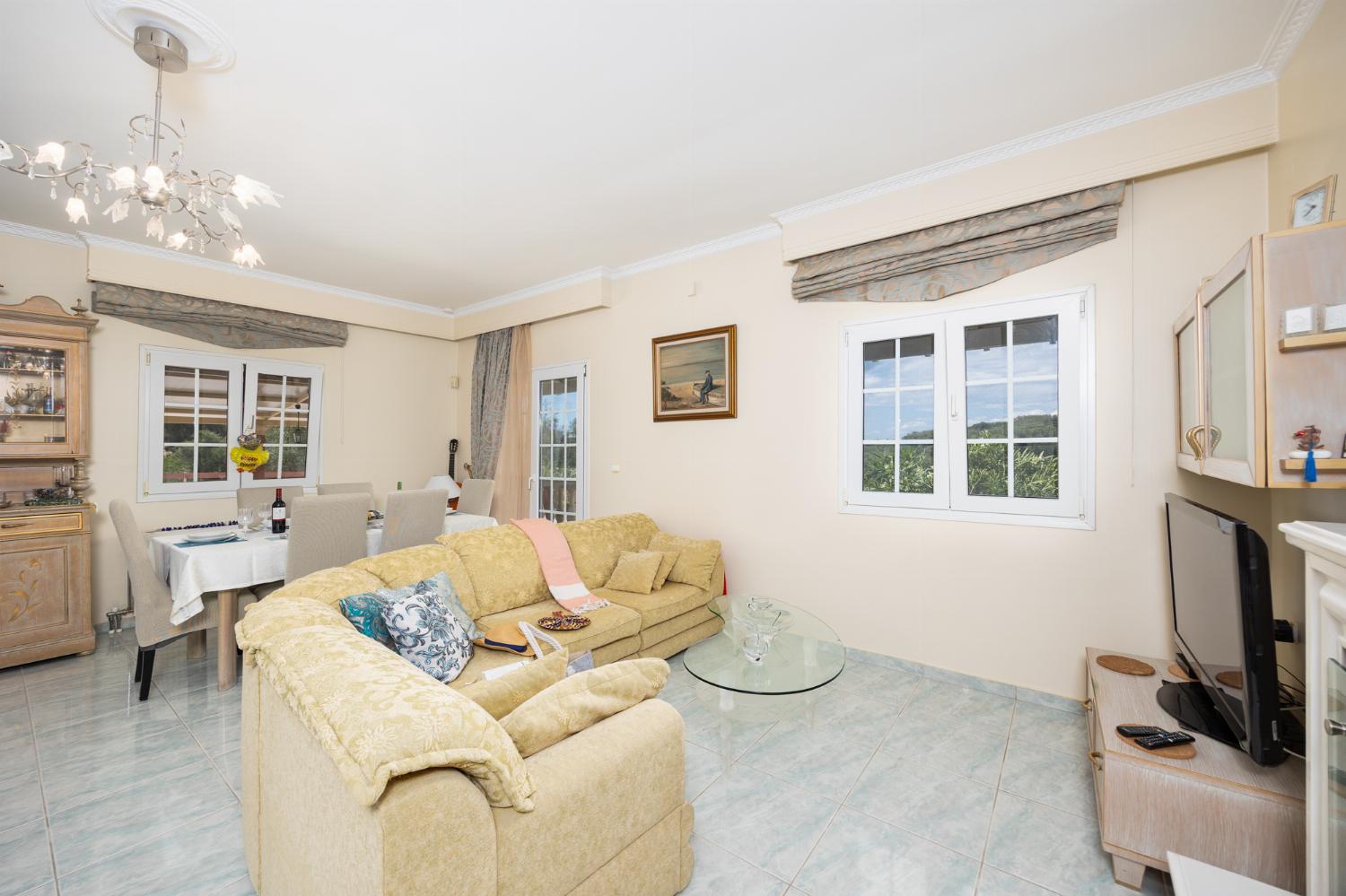 Open-plan living room with sofa, dining area, kitchen, ornamental fireplace, A/C, WiFi internet, and satellite TV