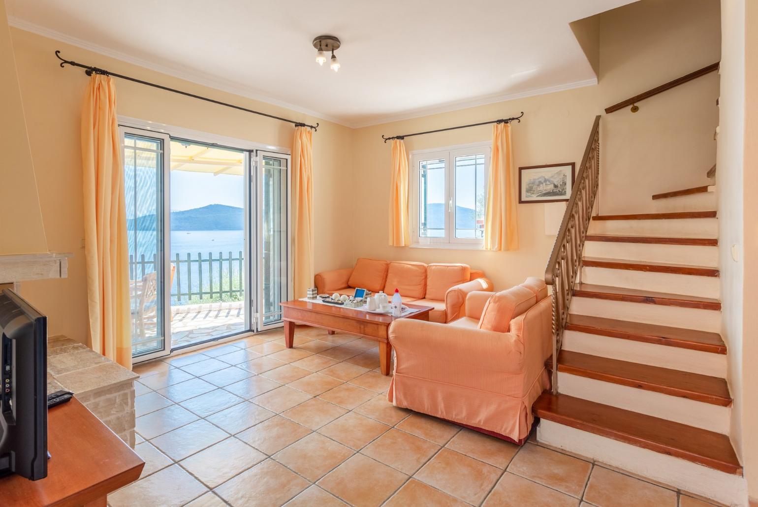 Open-plan living room with sofas, dining area, kitchen, ornamental fireplace, A/C, WiFi internet, satellite TV, and terrace access with panoramic sea views