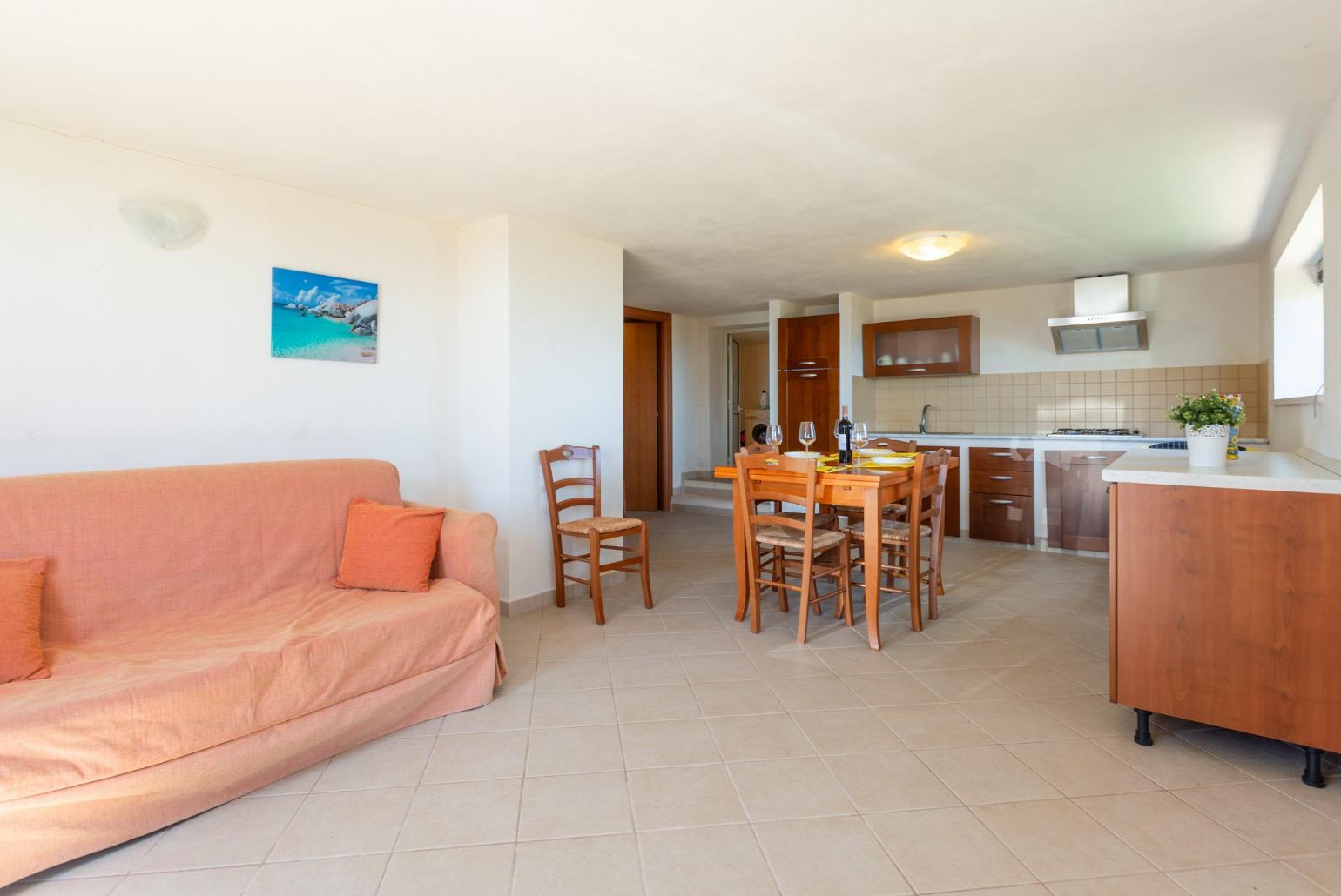 Open-plan living room on lower level with sofa, dining area, kitchen, and terrace access