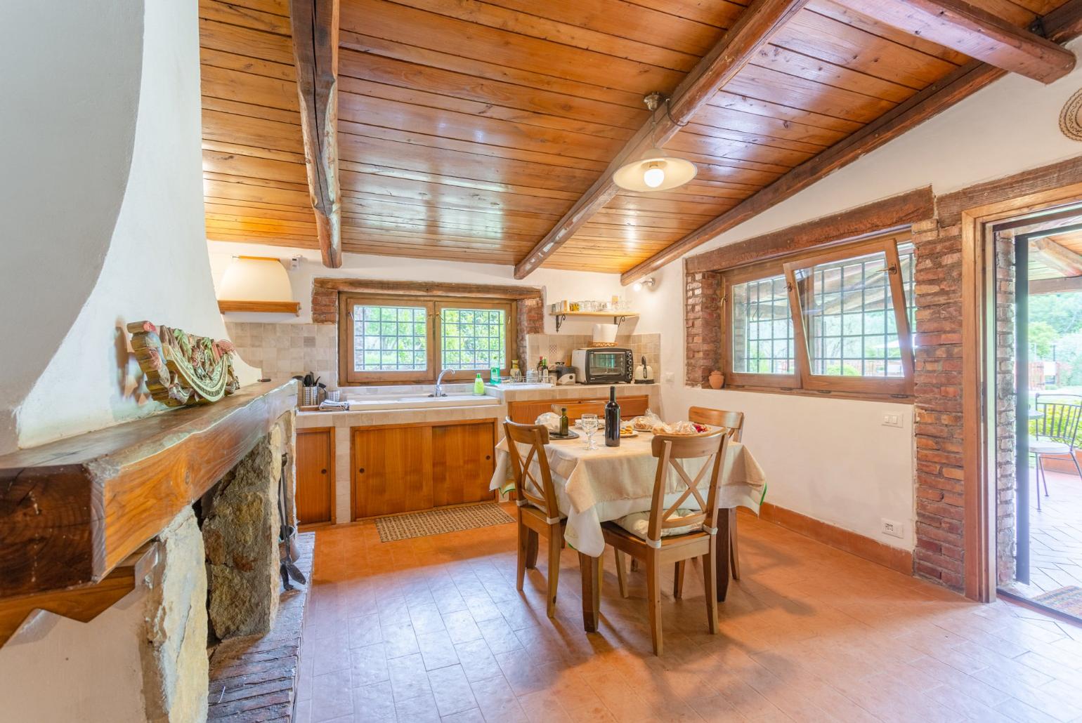 Open-plan living room with dining area, kitchen, ornamental fireplace, and terrace access