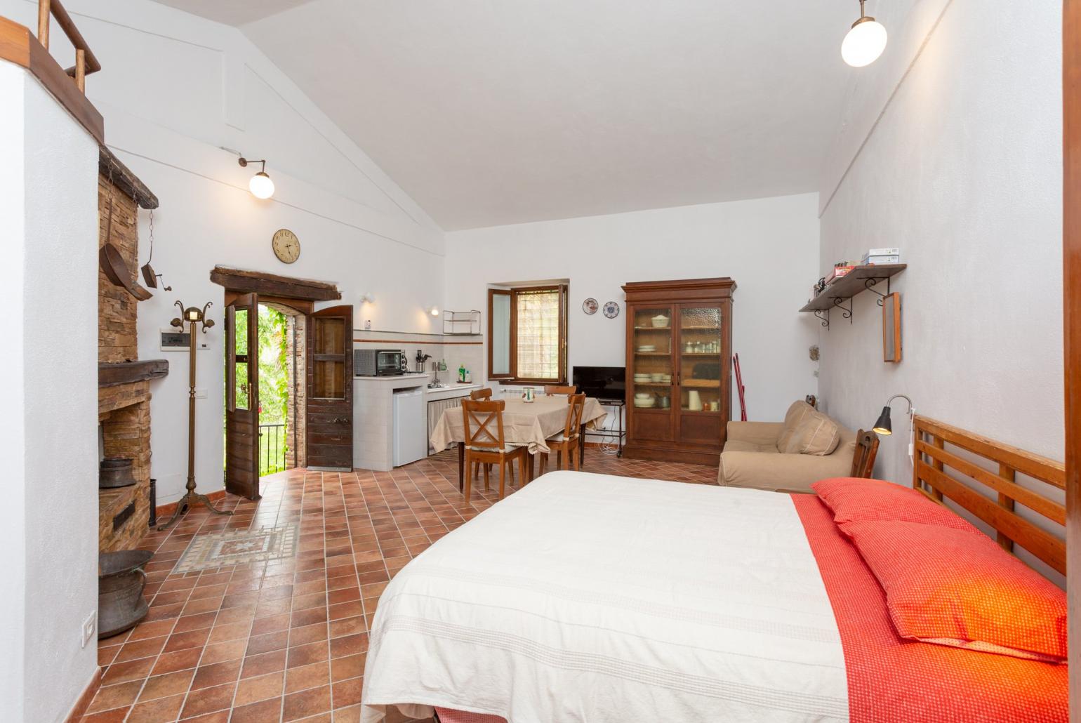 Open-plan room with double bed, dining area, sofa bed, kitchenette, and ornamental fireplace