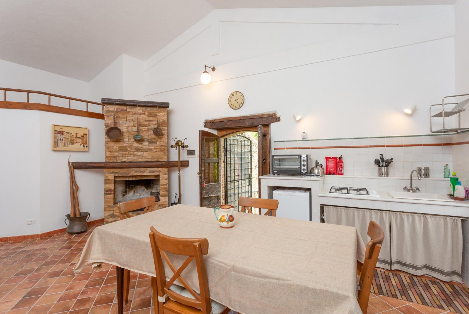 Open-plan room with double bed, dining area, sofa bed, kitchenette, and ornamental fireplace