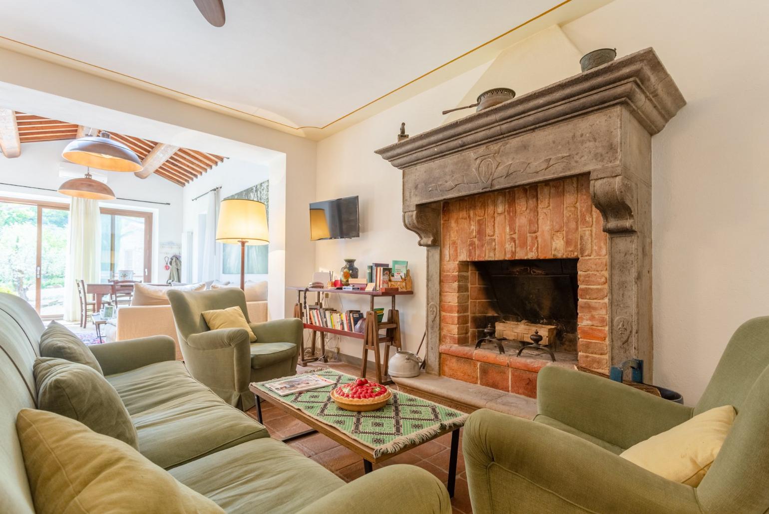 Living room on ground floor of main building with sofas, dining area, ornamental fireplaces, A/C, WiFi internet, satellite TVs, DVD player, and garden access 